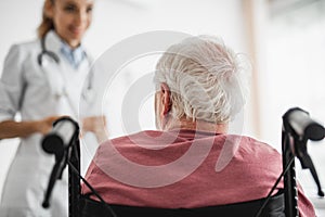 Patient sitting in wheelchair and looking at doctor