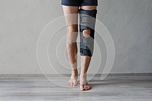 Patient standing with knee brace support after do posterior cruciate ligament surgery. Healthcare and medical concept