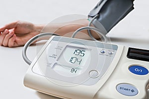 Patient suffers from hypertension. Woman is measuring blood pressure with monitor
