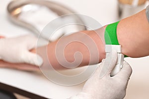 Patient with a tourniquet band on the arm, medical office or clinic