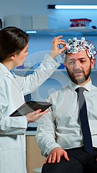 Patient wearing brainwave scanning headset discussing with neurological researcher