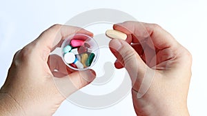 Patient woman holds medicine cup and a tablet of vitamin C in hands, ready to take medicines colorful pills, tablets and capsules