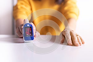 Patient woman using fingertip pulse oximeter oxygen saturation meter SPO2 PR blood monitor finger at home