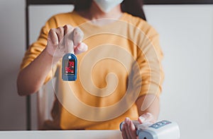 Patient woman using fingertip pulse oximeter oxygen saturation meter SPO2 PR blood monitor finger at home