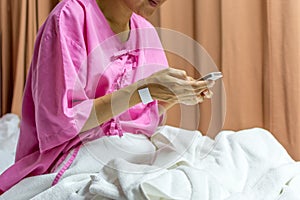 Patient woman using smartphone on bed