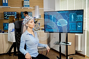 Patient woman who is brain scanned and his activity is shown on screen