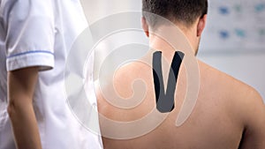 Patient with Y-shaped tape on upper back, doctors visit, alternative medicine