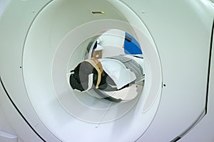 Patients screening on CT scanner. Man Undergoing CT Scan While Doctor`s Using Computers.
