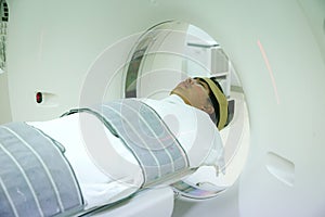 Patients screening on CT scanner. Man Undergoing CT Scan While Doctor`s Using Computers.