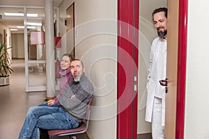 patients sit in the waiting room, doctor stands at the door