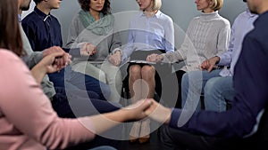 Patients sitting in circle and holding hands before collective therapy session