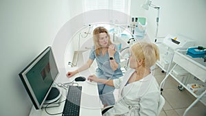 Between patients, two female doctors are talking in the office.