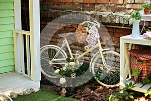 Patio of house with garden plants and bicycle. white vintage bicycle against brick wall. Old bicycle parked against a stone wall i