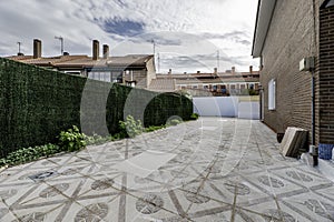 Patio of a single-family home with terrazzo floors surrounding the building built with dark brown cement bricks and a wall covered