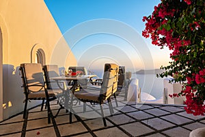 Patio with table and chairs decorated with beautiful bougainvillea flowers at Santorini island, Greece