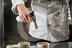 Patissier or chef burning creme brulee doing dessert photo