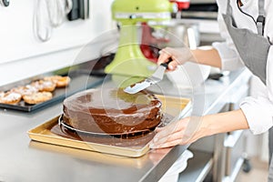Patissier pouring liquid chocolate on a cake