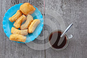 Patonggo on a blue plastic plate and black coffee on a wooden background