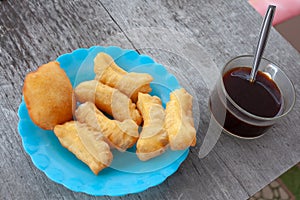 Patonggo on a blue plastic plate and black coffee on a wooden background