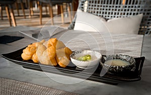 Patonggo or deep-fried dough sticks on black dish with pandan and sweet condense milk dipping on table