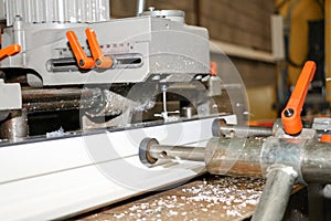 A machine produces profiles in a PVC joinery for the construction of windows or doors photo