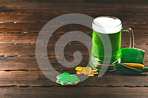 Patrick`s day background with a Glass of green beer and clover gingerbread with gold coins on wooden