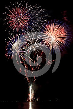 Patriotic colored fireworks reflecting over water