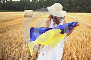 Patriotic Girl Flying Ukrainian Flag, Ukraine August 24 banner. Kid standing outdoors at sunset. International day of democracy