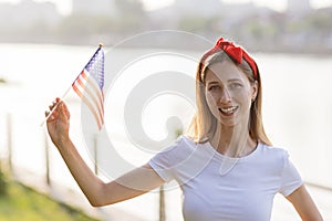 Patriotic holiday. Happy family, mother and daughter with American flag outdoors on sunset. USA celebrate independence