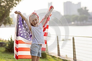 Patriotic holiday. Happy family, mother and daughter with American flag outdoors on sunset. USA celebrate independence