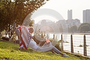 Patriotic holiday. Happy family, mother and daughter with American flag outdoors on sunset. USA celebrate independence