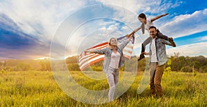 Patriotic holiday. Happy family, parents and daughters children girl with American flag outdoors. USA celebrate 4th of