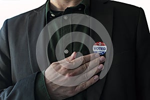 Patriotic man with usa I Voted sticker in his suit touching hand on his chest