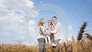 Patriotic Ukrainian family mother, father and daughter hugging in wheat field.