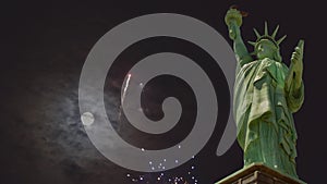 Patriotic US Holiday with fourth of july Statue of Liberty on fireworks exploding in mysterious night sky with over