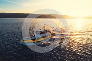 Patrol boat sailing at sunset in shining golden sea water