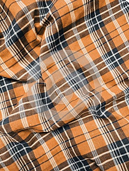 The pattern and background of the fabric has a orange checkered motif