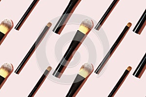 A pattern of black makeup brushes. Modern bright decorative background. Women`s accessories on a pink background. Professional