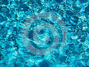 Pool water. Blue and turquoise pattern on surface. Blue colored pool water with bright and dark parts and sun reflections