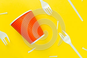 Pattern of broken plastic forks, and plastic cup on a yellow background.