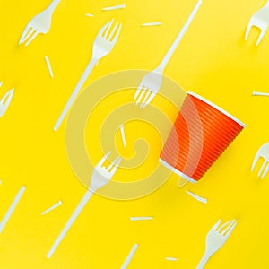 Pattern of broken plastic forks, and plastic cup on a yellow background.