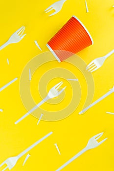 Pattern of broken plastic forks, and plastic cup on a yellow background.