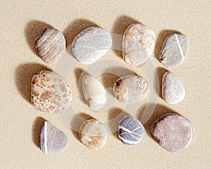 Pattern with close up pebble sea stones on sand texture. Square composition from natural stone colorful natural tones