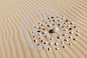 Pattern of colored pebbles in the shape of a circle on clean sand