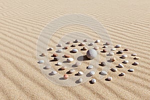 Pattern of colored pebbles in the shape of a circle on clean sand