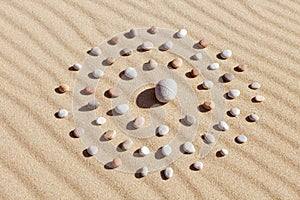 Pattern of colored pebbles in the shape of a circle on clean sand
