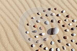 Pattern of colored pebbles in the shape of a circle on clean sand