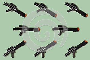 Pattern created of black rifle toys. A top view with pastel green background