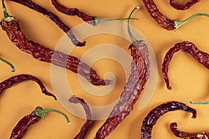 Pattern of dry red hot chili peppers on a orange background, top view, flat lay, close-up