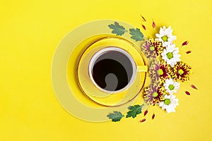 Pattern of flowers of red and white asters, green leaves and a cup of hot coffee Americano on yellow background